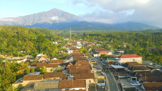 A beautiful village lies peacefully beneath Mount Arjuna, partially obscured by morning clouds.
