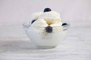 Creamy ice cream with blueberries in a glass bowl