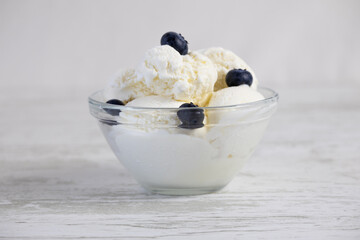 Creamy ice cream with blueberries in a glass bowl