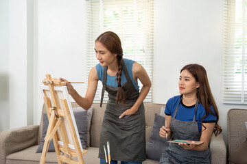 Lesbian artists collaborating on a canvas in a cozy living room