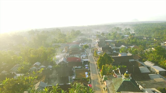 A beautiful village lies peacefully beneath Mount Arjuna, partially obscured by morning clouds.