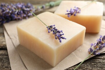 Aromatic soap bars and lavender flowers on wooden table, closeup