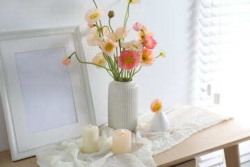 Bouquet of beautiful poppy flowers, frame and burning candles on table indoors