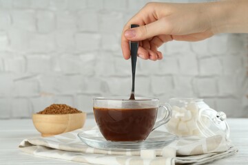 Woman making instant coffee at light table, closeup
