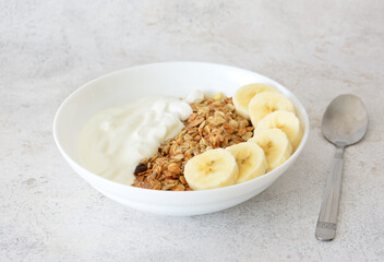 Healthy Breakfast Bowl with Granola, Yogurt and Banana Slices with a spoon