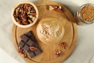 Delicious dalgona coffee in glass, pieces of chocolate, walnuts and granules on table, flat lay