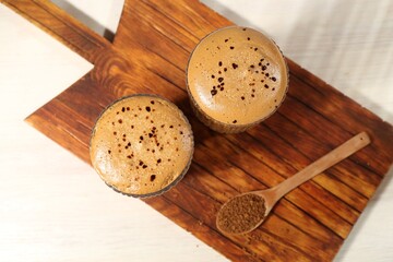 Delicious dalgona coffee in glasses and granules on light table, top view