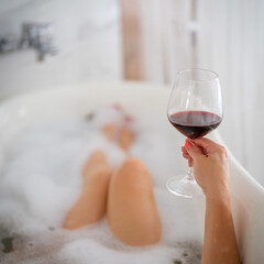 Close-up of female legs with red shoes and glass of wine