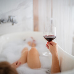 Close-up of female legs with red shoes and glass of wine