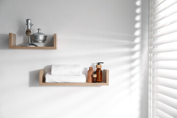 Wooden shelves with bathroom necessities on white wall