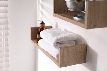 Wooden shelves with bathroom necessities on white wall