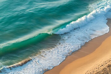 Turquoise ocean wave crashing onto a golden sandy beach with white foam
