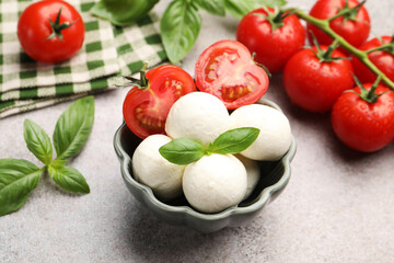 Tasty mozzarella cheese balls, tomatoes and basil on grey table, closeup