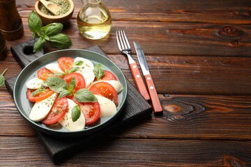 Tasty salad Caprese served on wooden table. Space for text