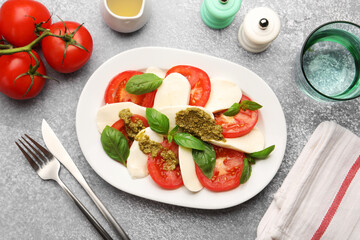 Tasty salad Caprese served with pesto sauce on grey table, flat lay