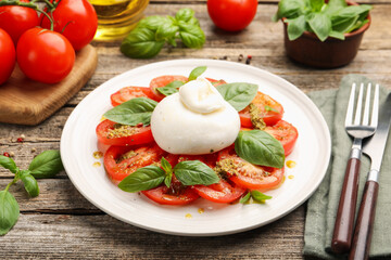Tasty salad Caprese served with pesto sauce on wooden table, closeup