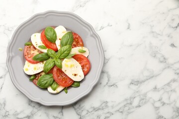 Tasty salad Caprese with mozzarella, tomatoes, basil and spices on white marble table, top view. Space for text