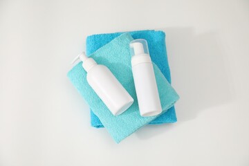 Stack of colorful towels and cosmetic products on white table, top view