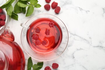 Tasty raspberry tea, berries and leaves on white marble table, flat lay. Space for text