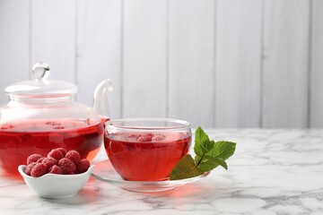 Tasty raspberry tea, berries and leaves on white marble table, closeup. Space for text