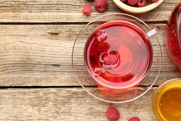 Tasty raspberry tea and berries on wooden table, flat lay. Space for text