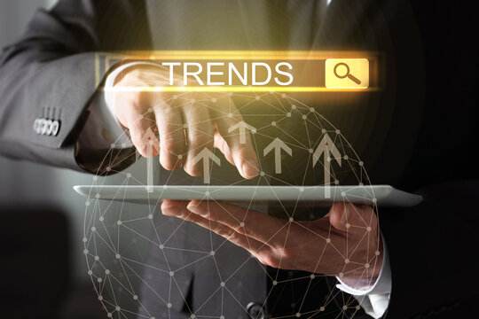 Businessman using tablet computer to find hot tendencies, new ideas, popular directions, closeup. Search bar with word Trends, arrows and globe