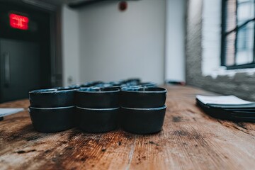 Stacks of dark bowls on a wooden table in a room