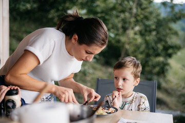 Mother serving lunch to her son on a terrace overlooking nature