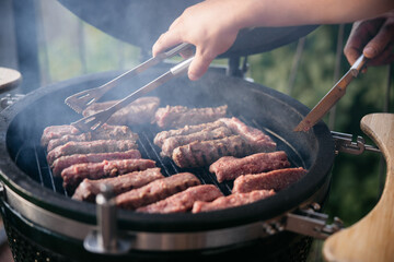Chefs grilling kebabs on a barbecue with tongs and knife