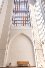 Architecture of calm. Wooden bench in white church. Aesthetic of light and space