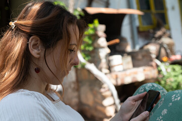 Beautiful adult woman using phone and smiling in the garden