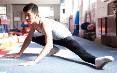 Athlete performing stretching exercises in gymnastics gym