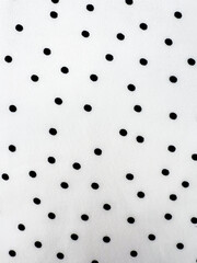 A detailed close-up of soft white satin fabric with classic black polka dots. Elegant, retro-style textile background for fashion or design use