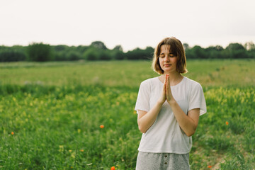 Teenager Girl closed her eyes, praying. Hands folded in prayer concept for faith, spirituality and...