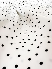 A detailed close-up of soft white satin fabric with classic black polka dots. Elegant, retro-style textile background for fashion or design use