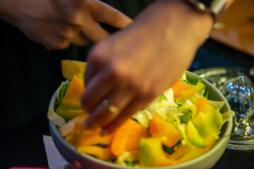 A vibrant kitchen scene of a woman slicing cucumbers, lettuce, and other vegetables, capturing the freshness and healthiness of a homemade salad in progress.
