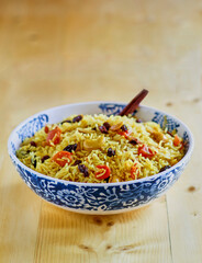 Indian vegetable biryani made with rice, raisins, carrot, onion, and chopped nuts