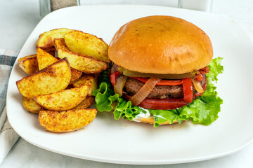portobello burger top with peppers and onions with potato wedges