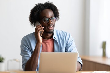 Man working remotely on laptop while talking on phone home office productivity focus