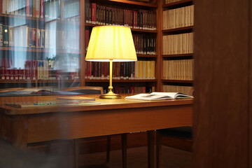 Library desk with lamp and books reading