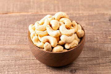 Organic roasted cashew nuts in a wooden bowl. Top view. 