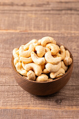 Organic roasted cashew nuts in a wooden bowl. Top view. 
