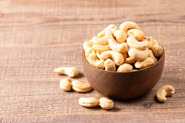 Organic roasted cashew nuts in a wooden bowl. Top view. 