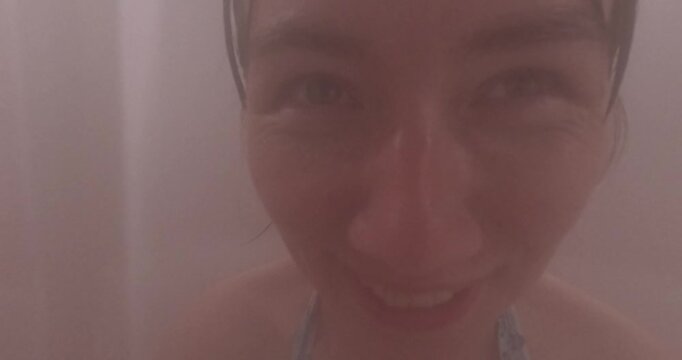 Women wearing swimming goggles smiling, enjoying steam room warmth, relaxing together in wellness spa environment