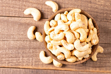Organic roasted cashew nuts in a wooden bowl. Top view. 