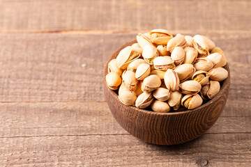 Organic roasted pistachio nuts in a wooden bowl. Top view. 