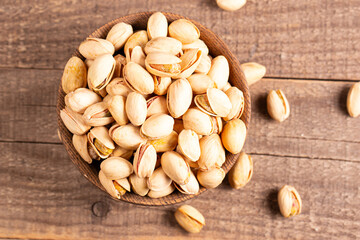 Organic roasted pistachio nuts in a wooden bowl. Top view. 