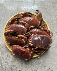 Live crabs stacked tightly on woven tray.