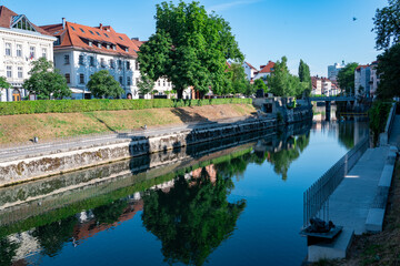Obraz premium Idyllic Riverside Scene of Ljubljana with Historic Architecture and Clear Reflections in Summer