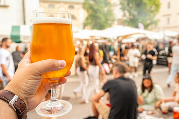 Golden Beer Glass Held at Outdoor Social Gathering Amidst Lively Ljubljana Atmosphere